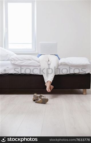 Woman using laptop on her bed
