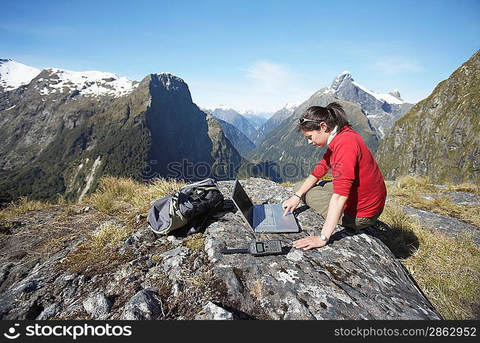 Woman using laptop on mountain peak