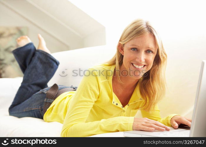 Woman Using Laptop Relaxing Sitting On Sofa At Home