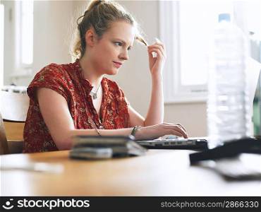 Woman using laptop sitting at dining table low angle view