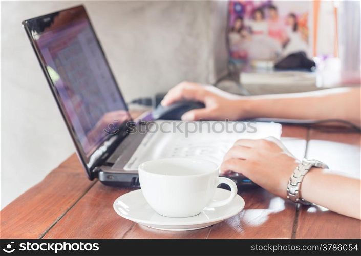 Woman using laptop with a cup of coffee, stock photo