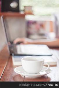 Woman using laptop with a white cup of coffee, stock photo
