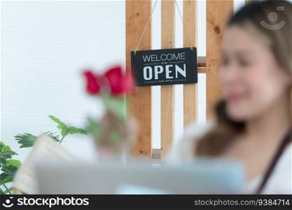 Woman using laptop with open sign in floral shop. Business concept.