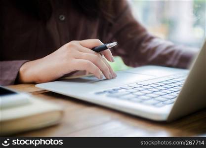 woman using laptop with smart phone and notebook selected focus on hands.