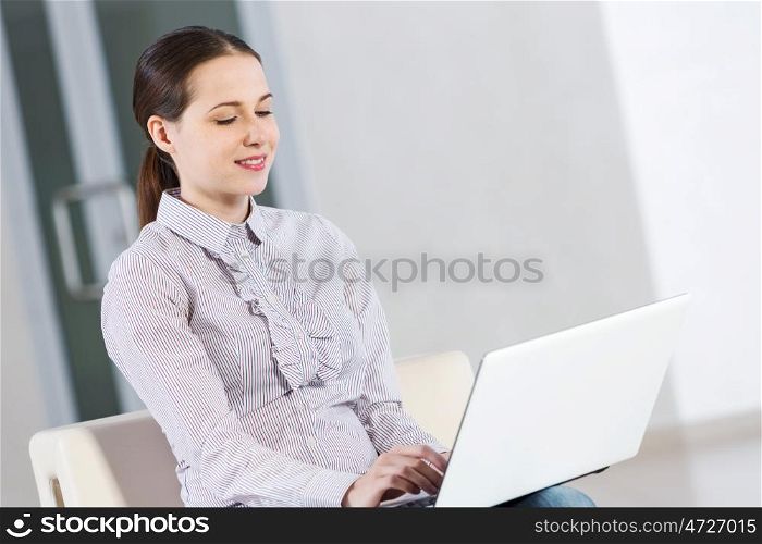 Woman using laptop. Young pretty girl in casual sitting and using laptop