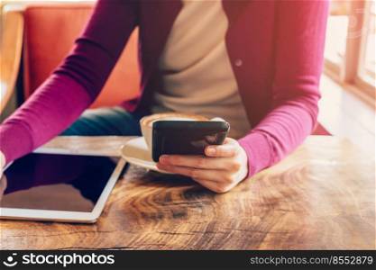Woman using mobile phone in cafe. Female with tablet and coffee.