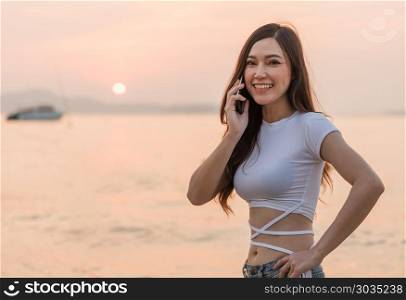 woman using mobile phone on the sea beach with sunset. beautiful woman using mobile phone on the sea beach with sunset