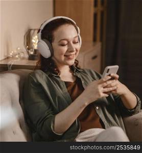woman using modern headphones smartphone device home