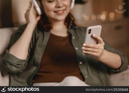 woman using modern headphones smartphone device home sofa