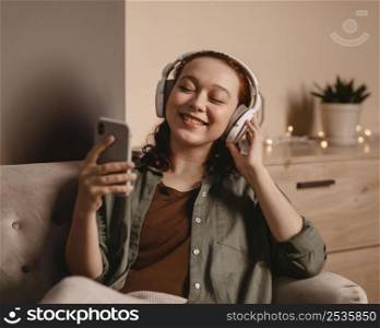 woman using modern headphones smartphone home