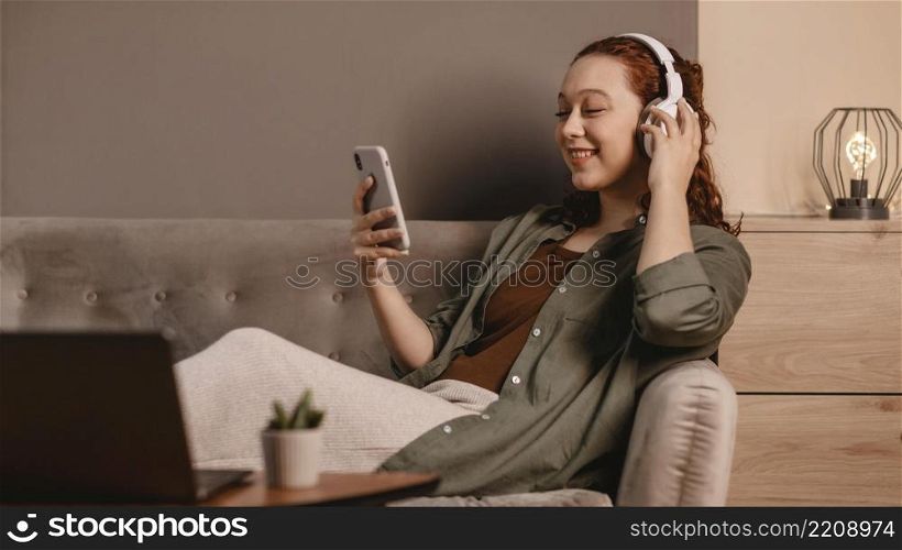 woman using modern headphones smartphone sofa home