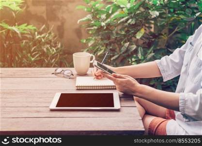 Woman using phone on table wood in garden at coffee shop with vintage toned.