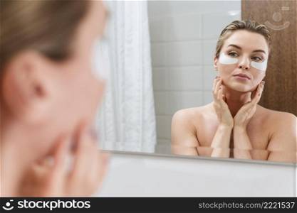 woman using reducing dark circles patches bathroom