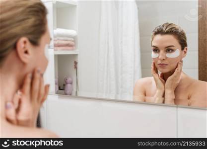 woman using reducing dark circles patches mirror