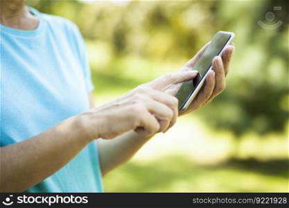 Woman using smart phone with blank black screen at outdoor with nature background