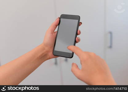 woman using smartphone office supplies technological devices inside home. Young lady using a dark smartphone inside home. Woman holding a black cell phone in a house ambient. Girl with technological devices and office supplies with blank space.