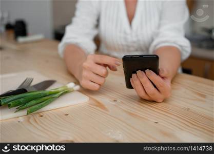 woman using smartphone office supplies technological devices inside home. Young lady using a dark smartphone inside home. Woman holding a black cell phone in a house ambient. Girl with technological devices and office supplies with blank space.
