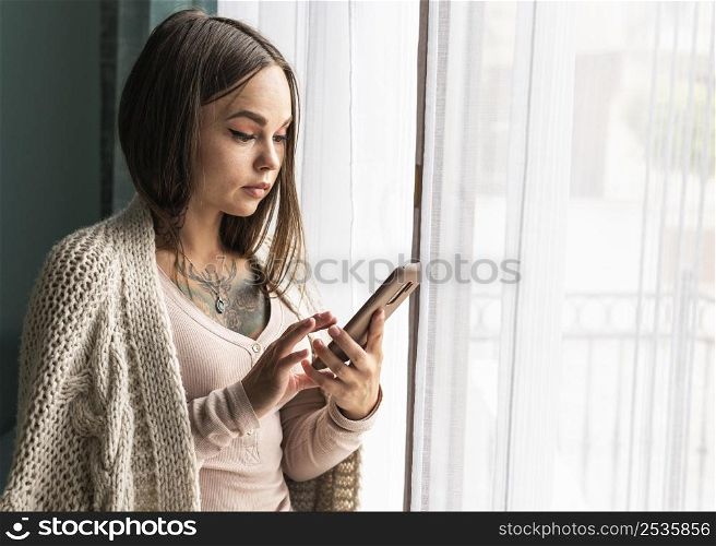 woman using smartphone window home during pandemic