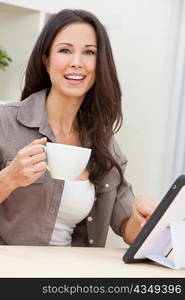 Woman Using Tablet Computer At Home Drinking Tea or Coffee