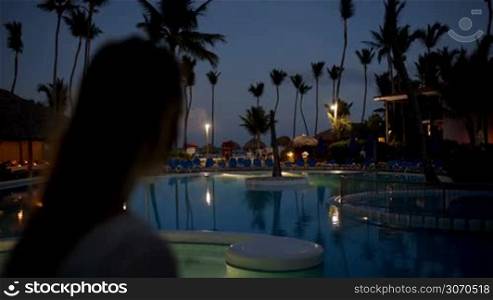 Woman using tablet computer to take photos on tropical resort in the evening