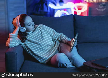 woman using tablet headphones home couch