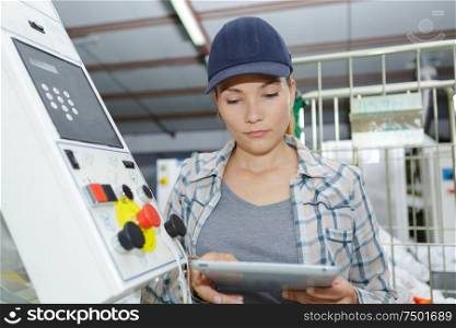woman using tablet next to machinery controls