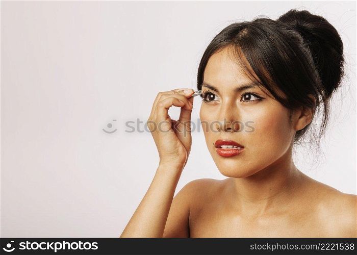 woman using tweezers her eyebrows
