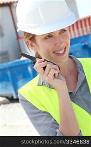 Woman using walkie-talkie on construction site