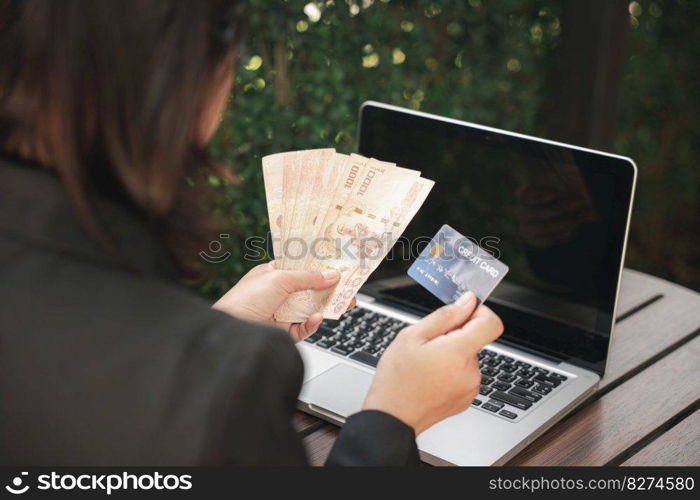 Woman using working and shopping outdoor at cafe coffee shop, Online e-commerce, internet banking, Hands of businesswoman holding thai money and credit card on laptop computer, technology finance