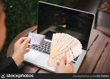 Woman using working and shopping outdoor at cafe coffee shop, Online e-commerce, internet banking, Hands of businesswoman holding thai money and credit card on laptop computer, technology finance