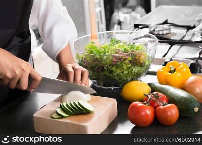 woman vegan cooking healthy food and preparing salad for dinner in a kitchen