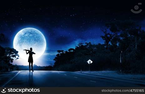 Woman violinist. Silhouette of woman playing violin at night