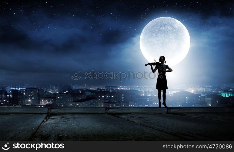 Woman violinist. Silhouette of woman playing violin at night