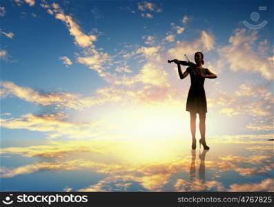 Woman violinist. Silhouette of woman playing violin at sunrise
