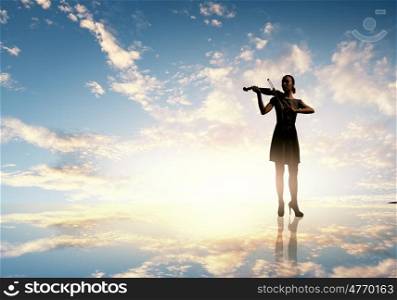Woman violinist. Silhouette of woman playing violin at sunset