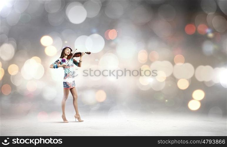 Woman violinist. Young attractive woman in colored dress playing violin