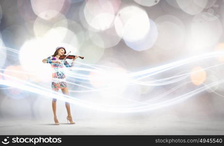 Woman violinist. Young attractive woman in colored dress playing violin