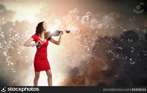 Woman violinist. Young attractive woman in red dress playing violin