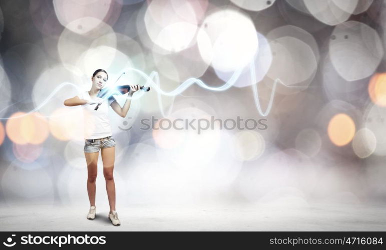 Woman violinist. Young attractive woman playing violin with bokeh lights at background