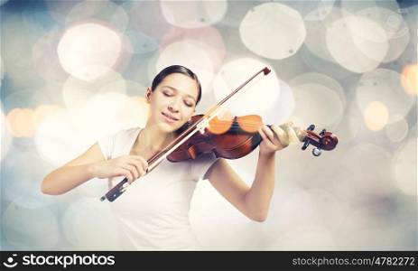 Woman violinist. Young attractive woman playing violin with bokeh lights at background