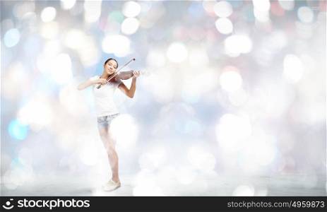 Woman violinist. Young attractive woman playing violin with bokeh lights at background