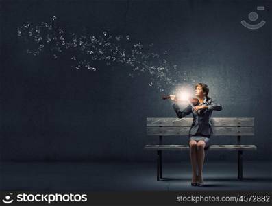 Woman violinist. Young businesswoman sitting on bench and playing violin