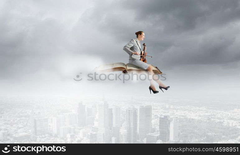 Woman violinist. Young businesswoman sitting on book and playing violin