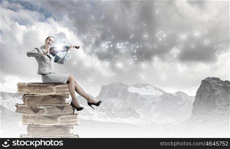 Woman violinist. Young businesswoman sitting on pile of books and playing violin