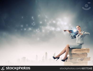 Woman violinist. Young businesswoman sitting on pile of books and playing violin