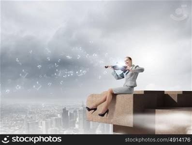 Woman violinist. Young businesswoman sitting on top of building and playing violin