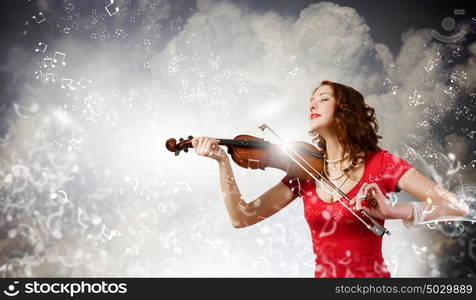 Woman violinist. Young pretty woman in red dress playing violin