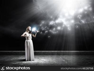 Woman violinist. Young woman in white dress playing violin