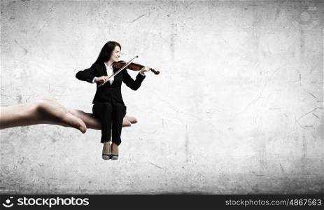 Woman violinist. Young woman sitting in palm and playing violin