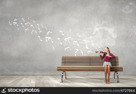 Woman violinist. Young woman sitting on bench and playing violin